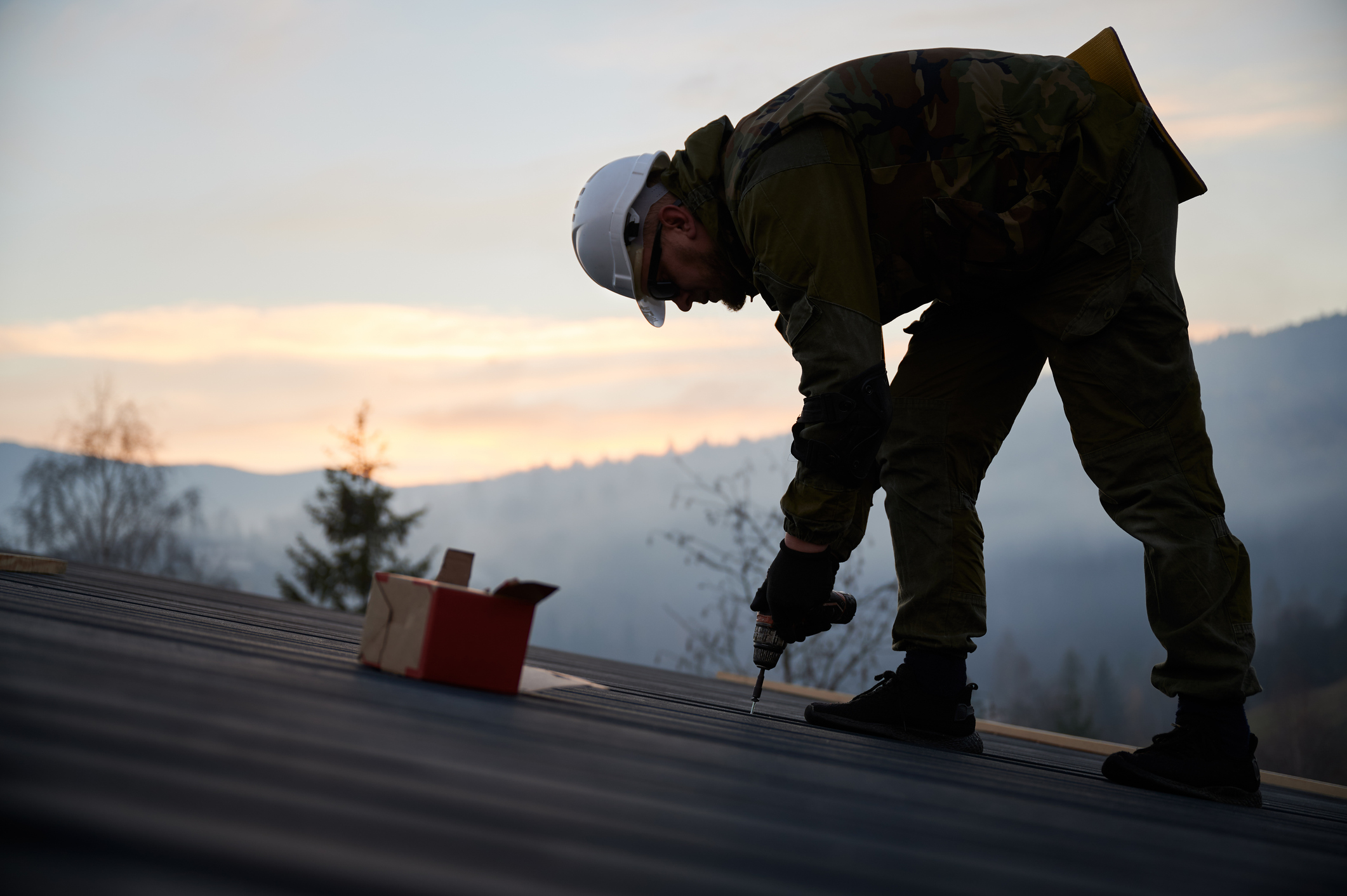 A Man with White Hard Hat Working on a Roof